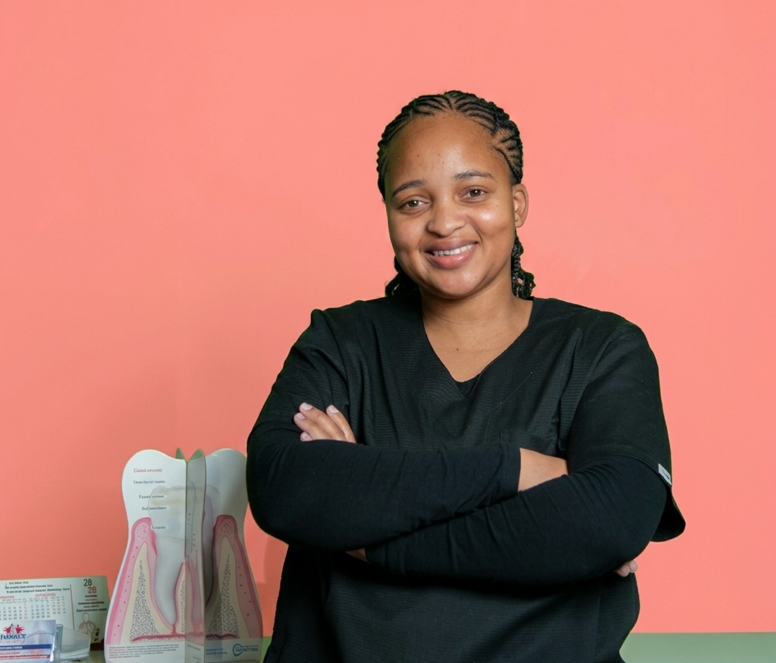 Tebogo Mongae, the dental secretary at Mahikeng Medical Center, smiling with arms crossed next to a dental model